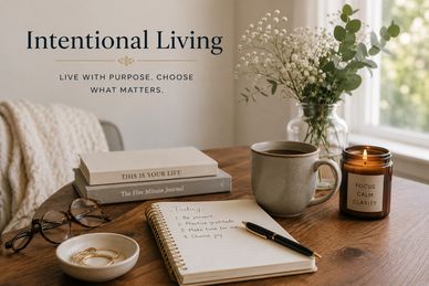 A wooden desk with a notebook, pen, candle, tea, and flowers, creating a calm space for reflection.