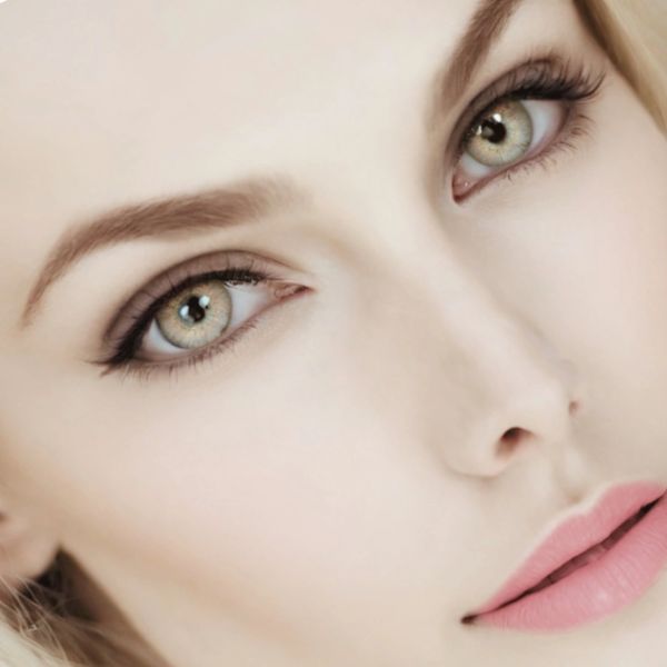 Close-up of a woman's face highlighting her green eyes and soft pink lips.