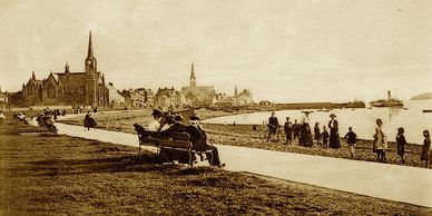 Vintage seaside promenade with church and people relaxing.