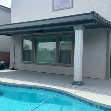 Backyard patio with covered seating area and pool.