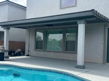 Backyard patio with covered seating area and pool.