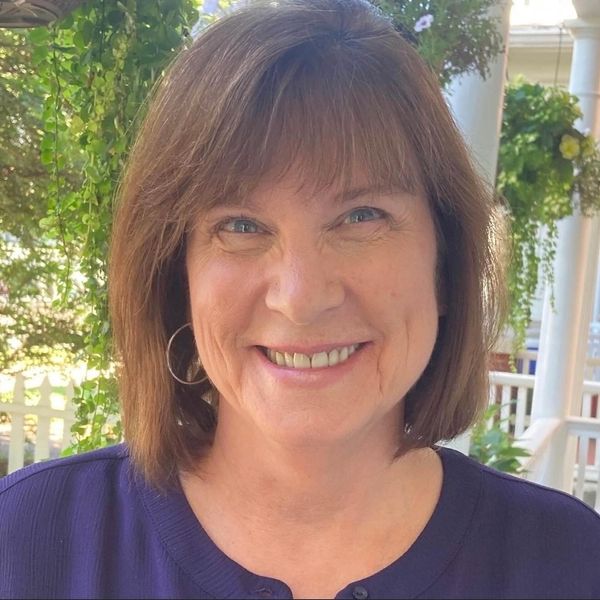 Smiling woman with brown hair outdoors.