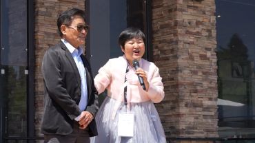Two people speaking with a microphone outdoors.