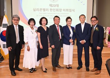 Group of seven people posing at an event with a presentation screen behind them.