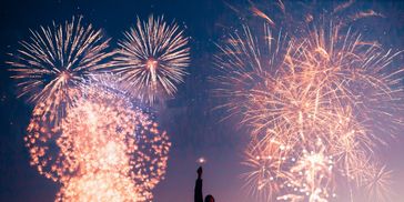 Person watching vibrant fireworks lighting up the night sky.