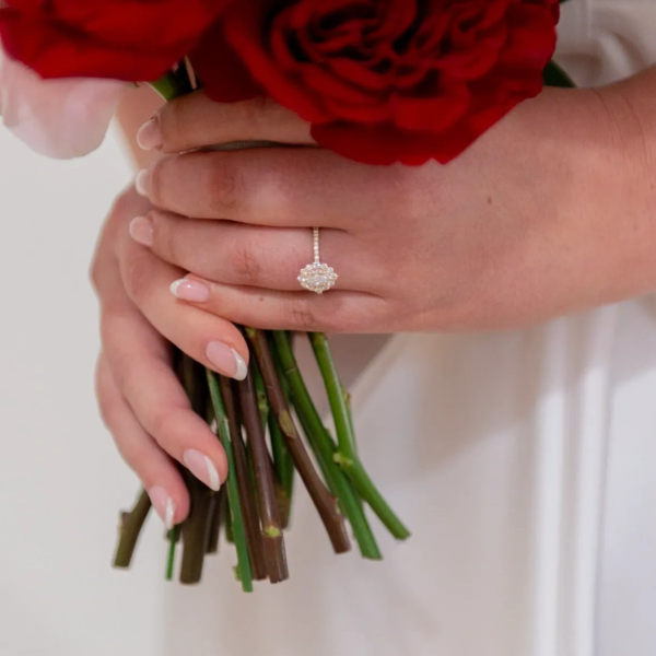 Hands holding red roses with an elegant ring on a finger.