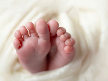 Close-up of tiny baby feet wrapped in a soft blanket.