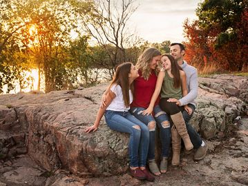 A family of four sitting on a rock at sunset, enjoying nature.
