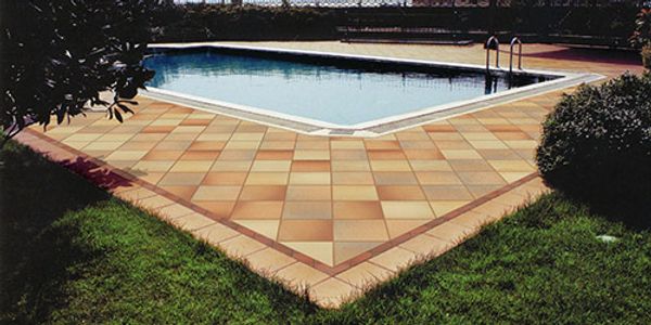 Square clay paving tiles around an outdoor swimming pool, with contrasting border courses