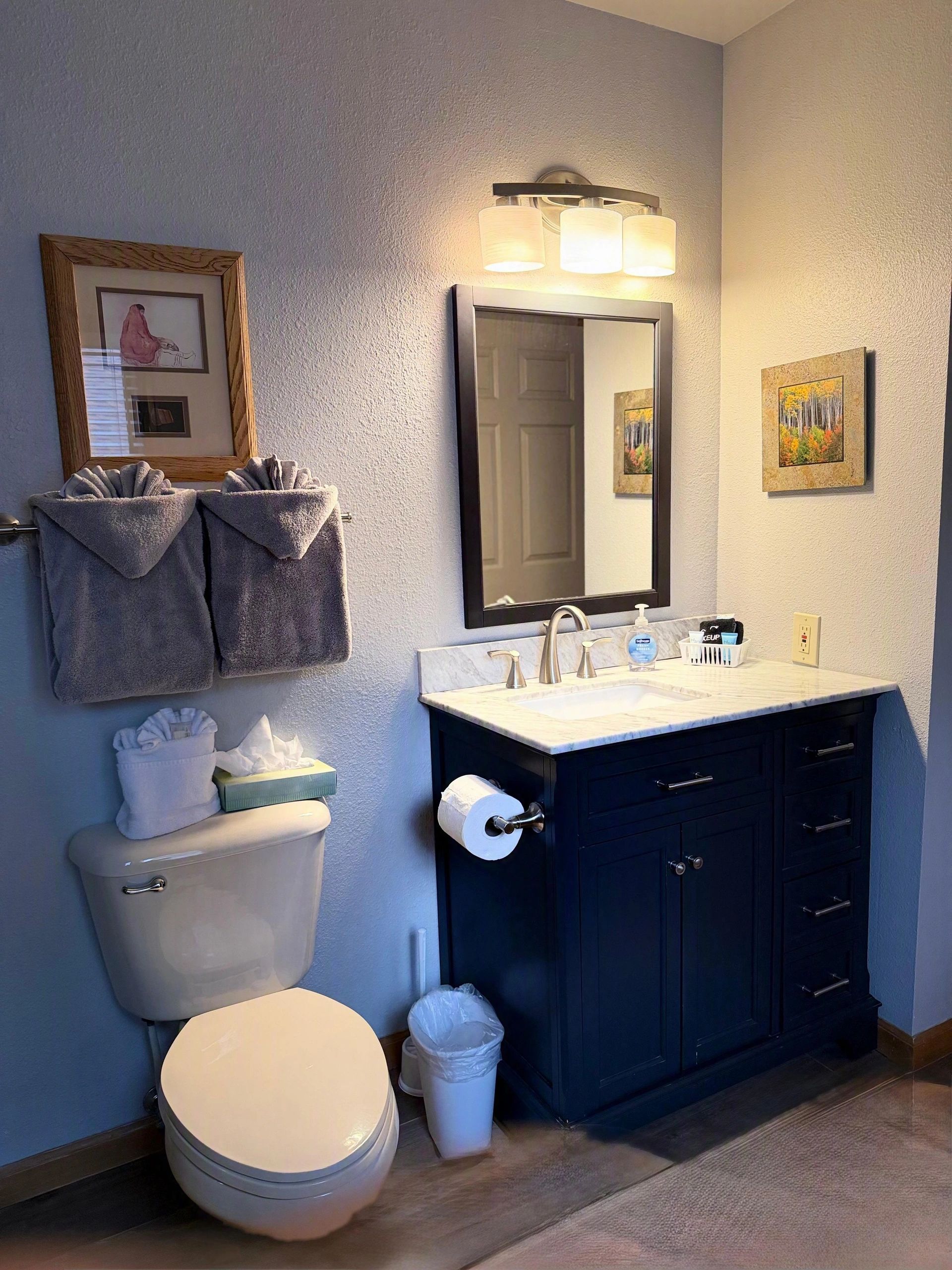 A standard hotel bathroom with a toilet, sink, and mirror.
