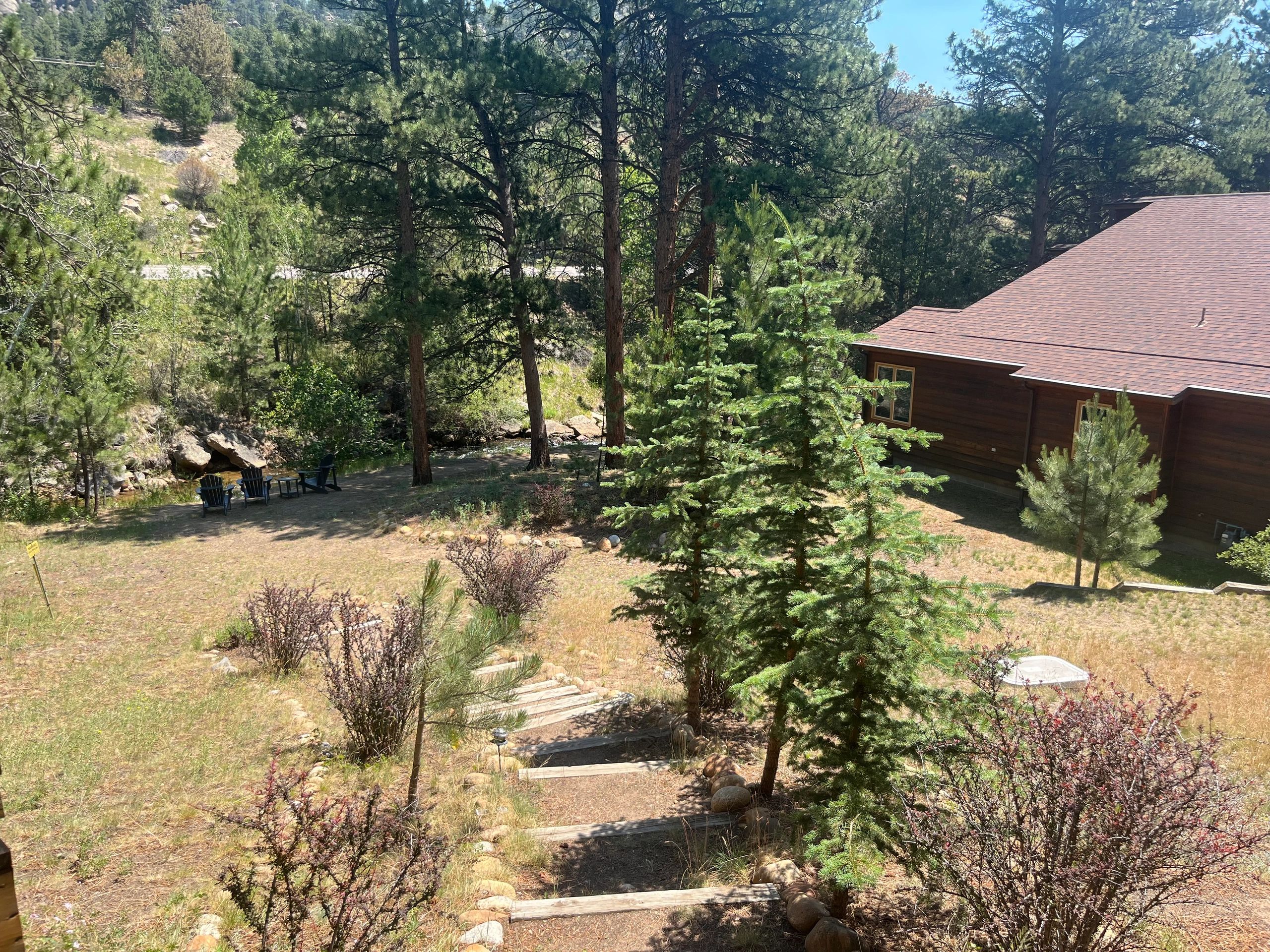 A brown wooden building with a brown roof surrounded by trees and a yard.
