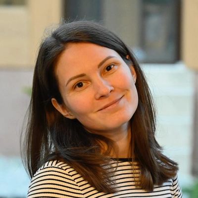 Woman with dark hair and striped shirt smiling.
