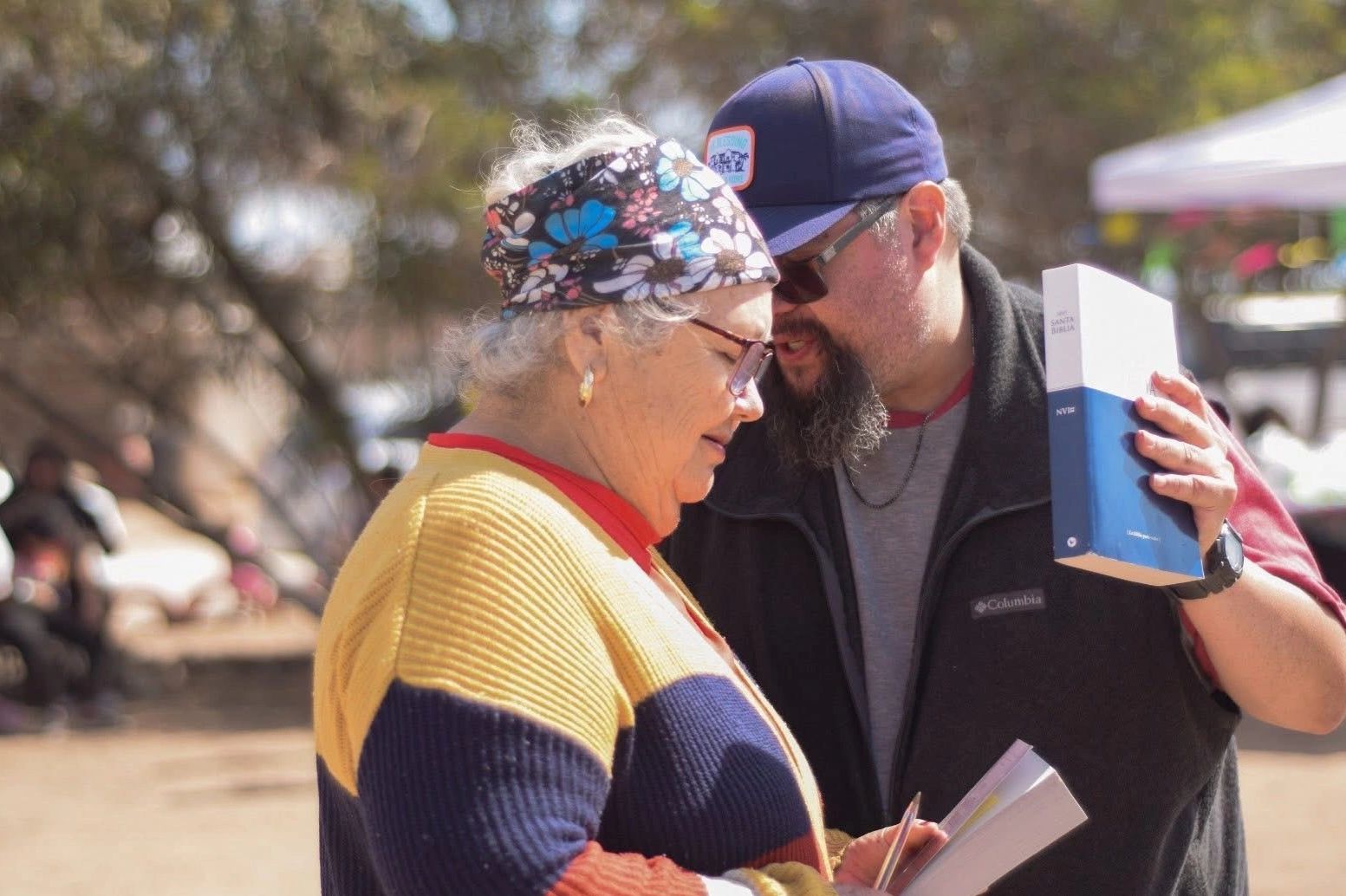 A man shows a woman a book while speaking closely.