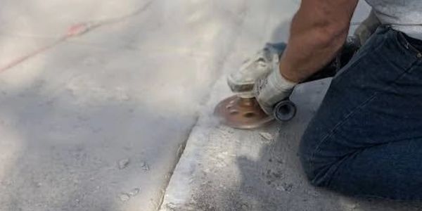 Buffalo Boys team member using a precision concrete grinder to repair a sidewalk trip hazard in WNY.