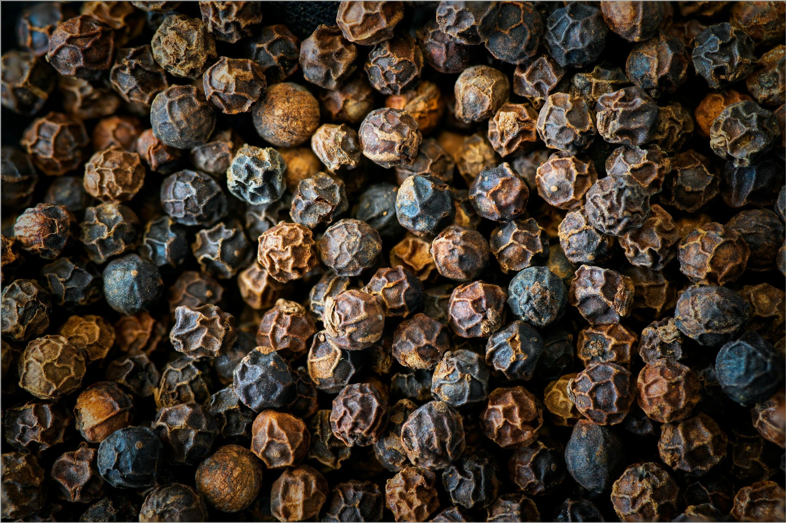 Close-up of black peppercorns with textured surfaces.