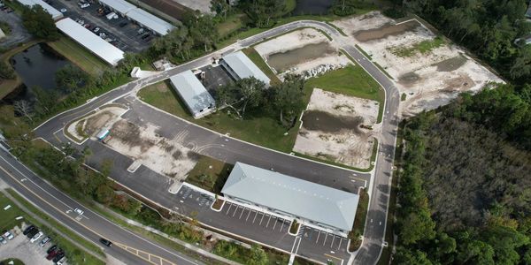 Aerial view of a commercial complex surrounded by roads and greenery.