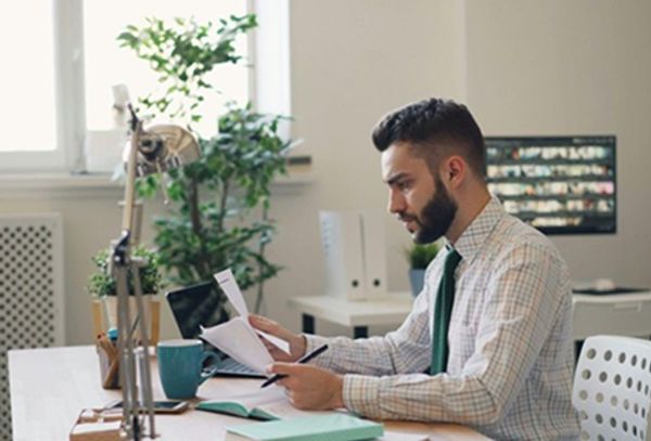 Man reviewing documents at a bright office desk.