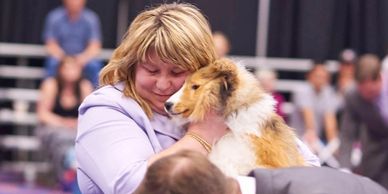 Woman affectionately holding a fluffy dog at an event.