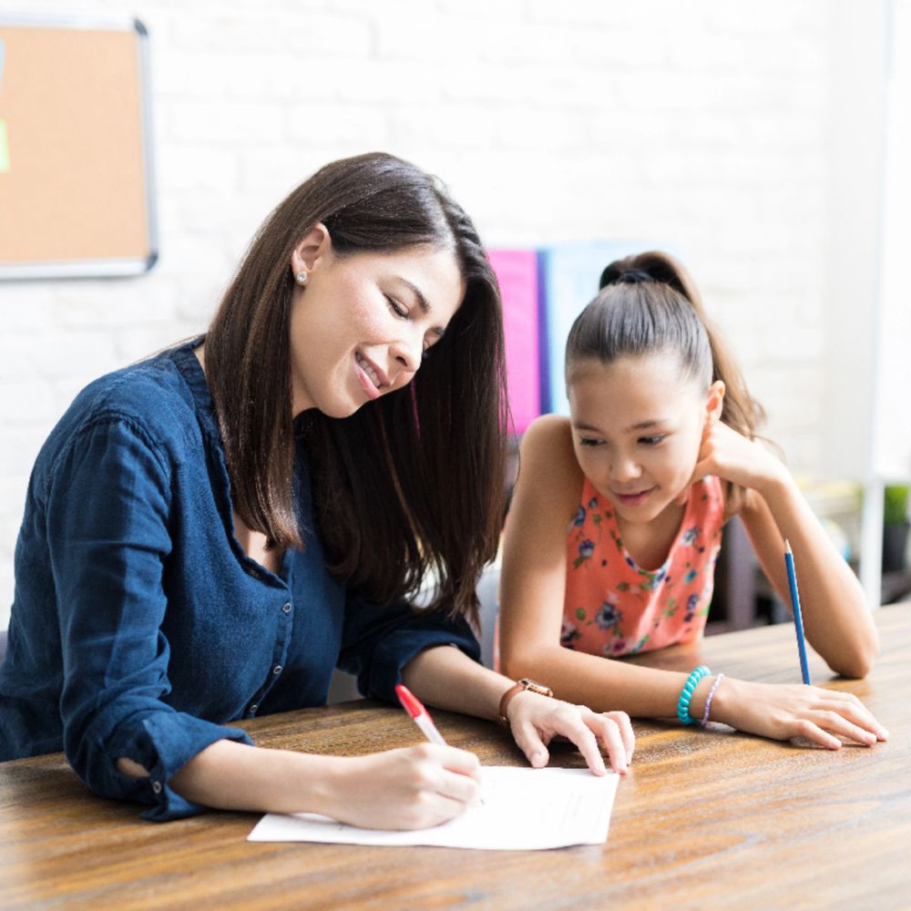 A teacher working one on one with a child helping them with schoolwork

