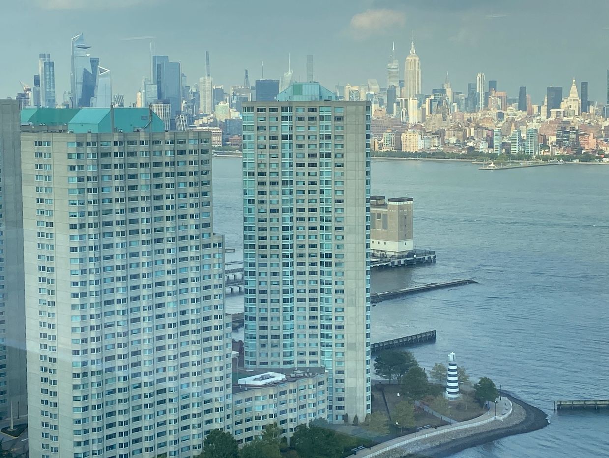 View of New York City skyline with waterfront and tall buildings.