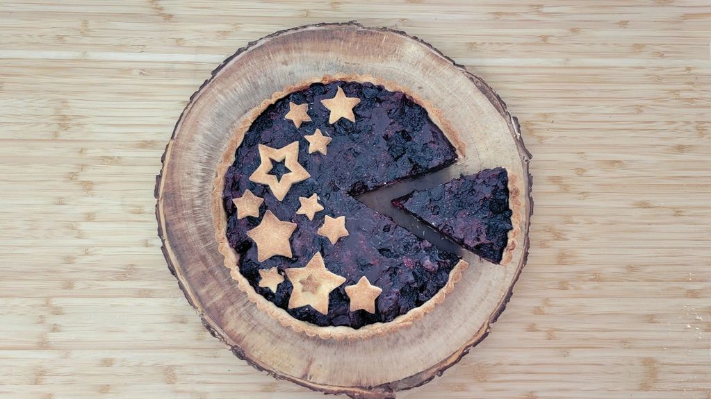 Blueberry pie with star-shaped crust decorations on a wooden board.