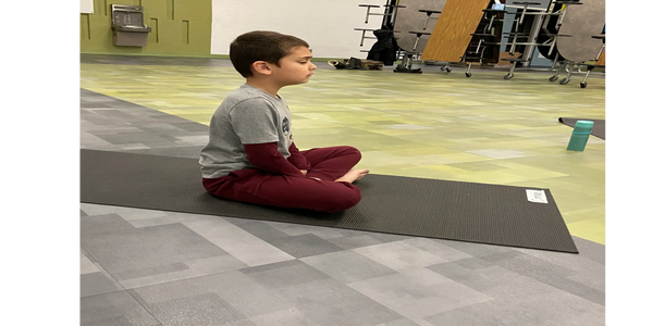 Boy sitting upright with eyes closed.