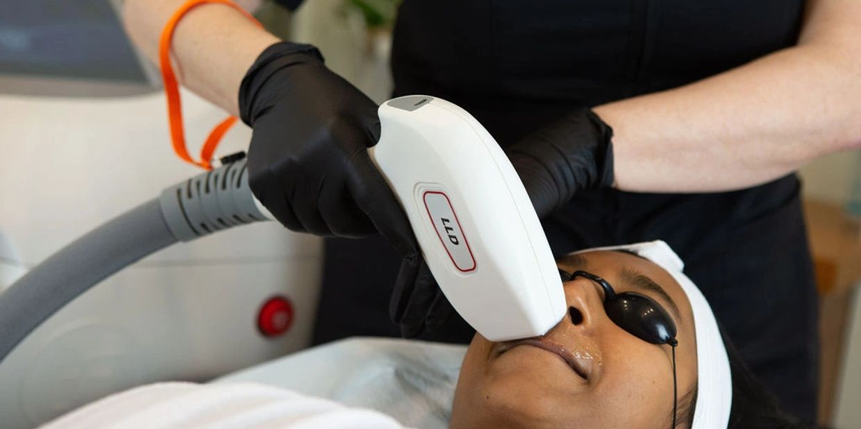 Laser hair removal treatment for a woman lying on a bed wearing goggles