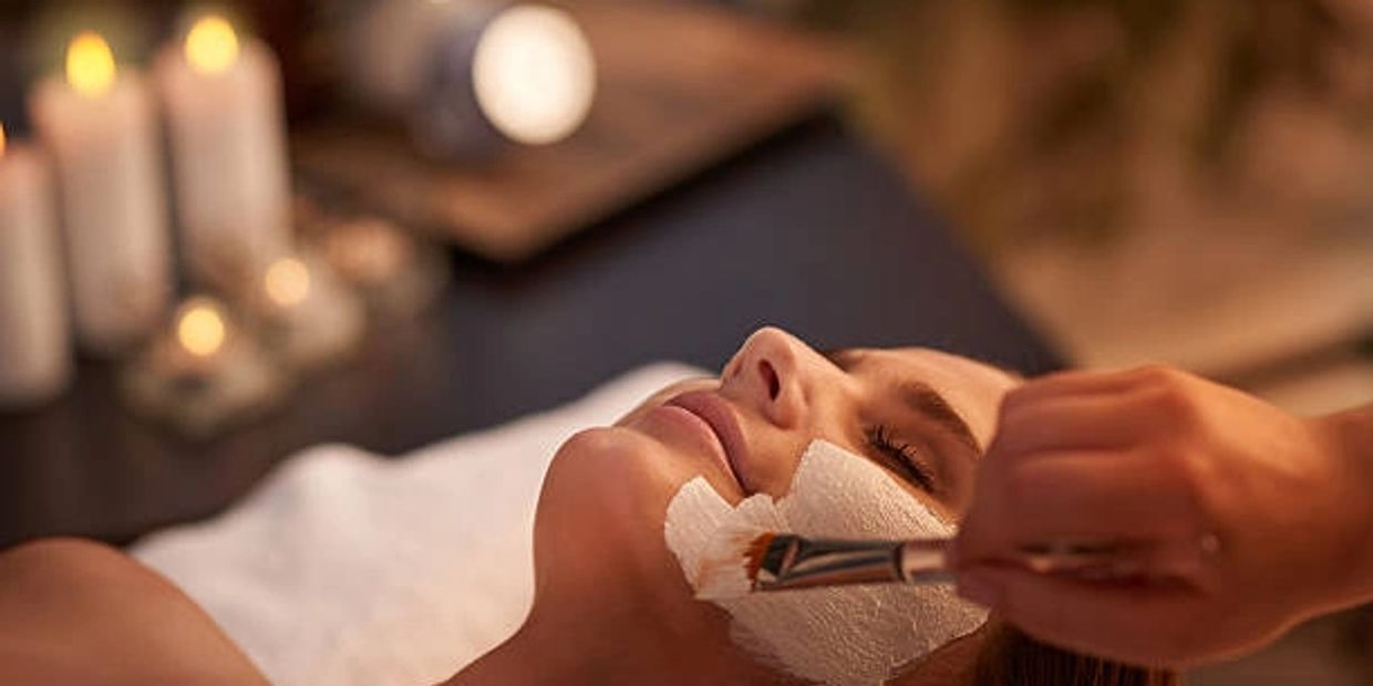 Express Glow facial image  a woman lying with an operator hand using a brush for applying face mask