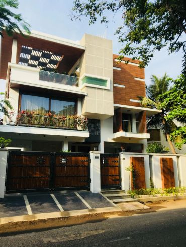Modern multi-story house with wooden and concrete facade under clear blue sky.