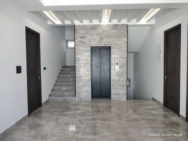 Modern interior with elevator and stairs in a clean hallway.