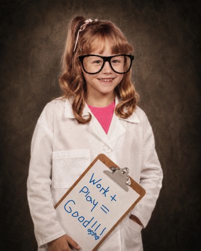 Young girl in lab coat holding clipboard with positive message.