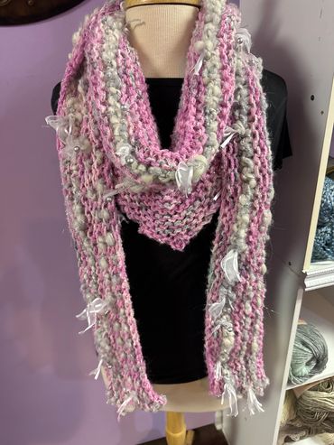 Handmade pink and cream knitted scarf with ribbon accents.