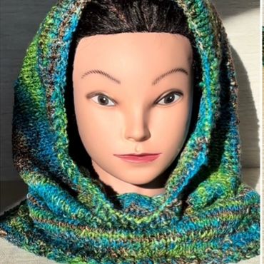Mannequin head wearing a multicolored knitted hood with shades of blue and green.