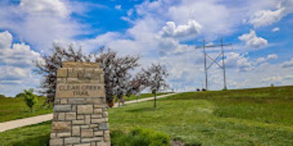 Clear Creek Trail entrance with stone sign and blue sky.
