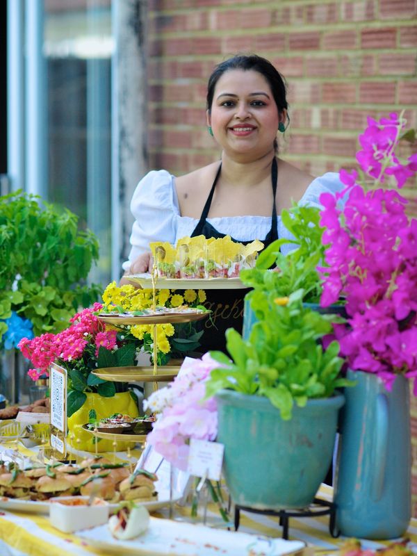 Woman smiling behind a table with food and flowers.
