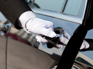 A gloved hand opening a car door handle.