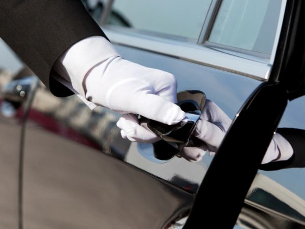 A gloved hand opening a car door handle.