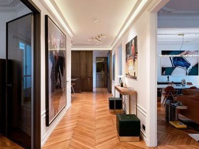 Modern hallway with wooden herringbone floor and contemporary art.