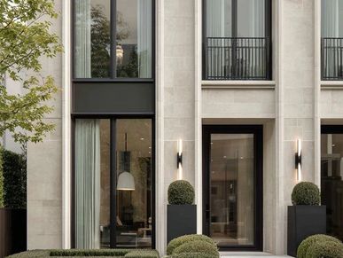 Modern stone facade with tall windows and elegant greenery.
