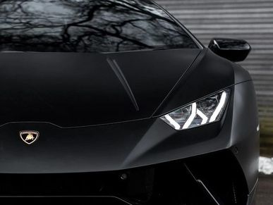 Close-up of a sleek black Lamborghini headlight and emblem.