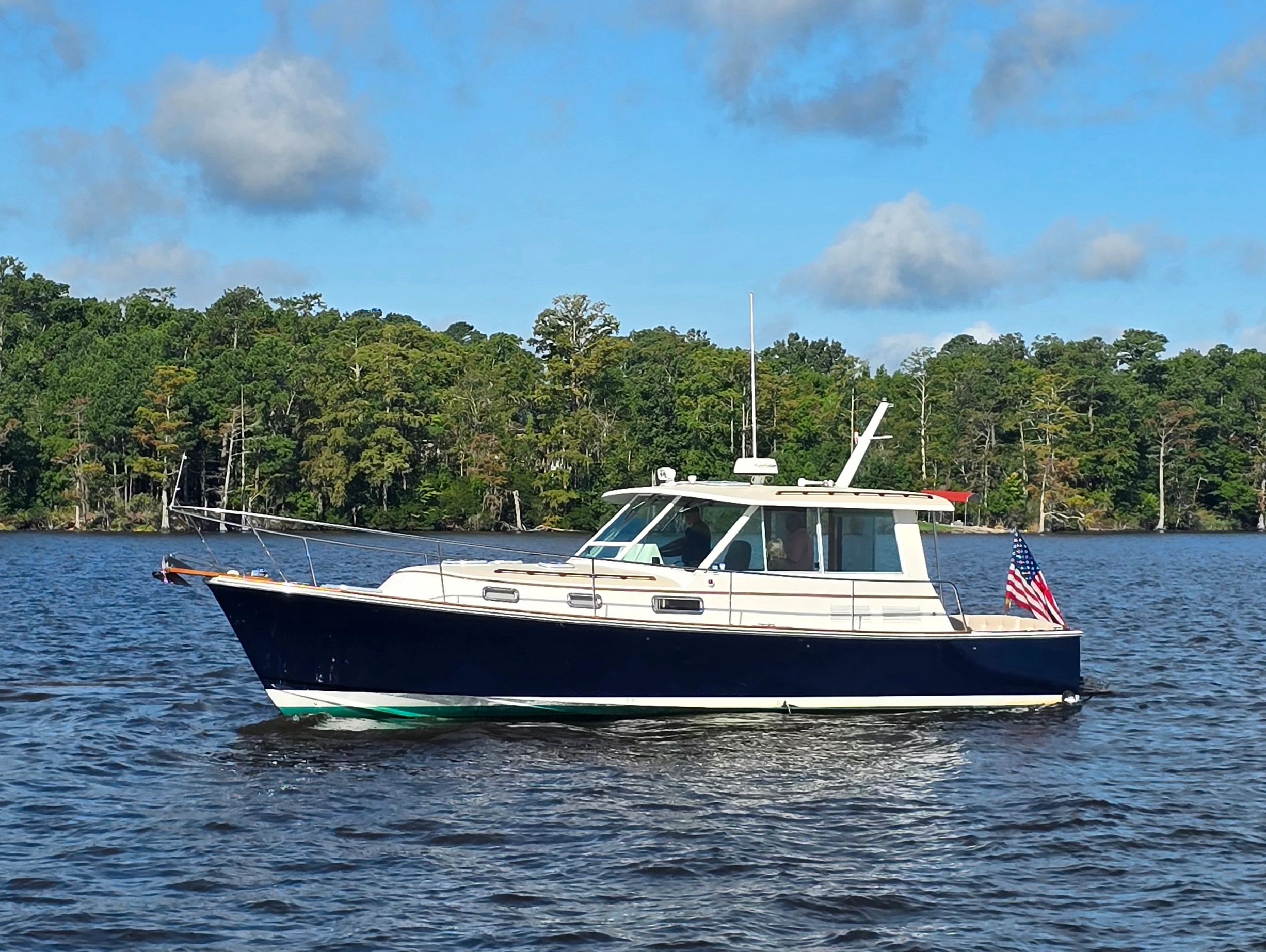 Motorboat cruising on a lake with trees in the background.