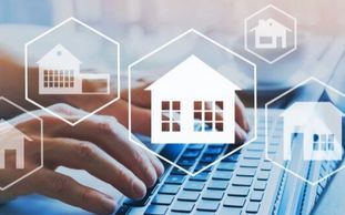 Person typing on a keyboard with house icons floating.