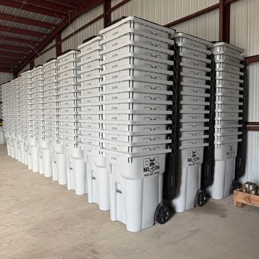 Rows of stacked gray trash bins inside a warehouse.