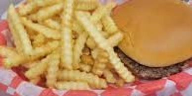 A hamburger with crinkle-cut fries on a red checkered paper.