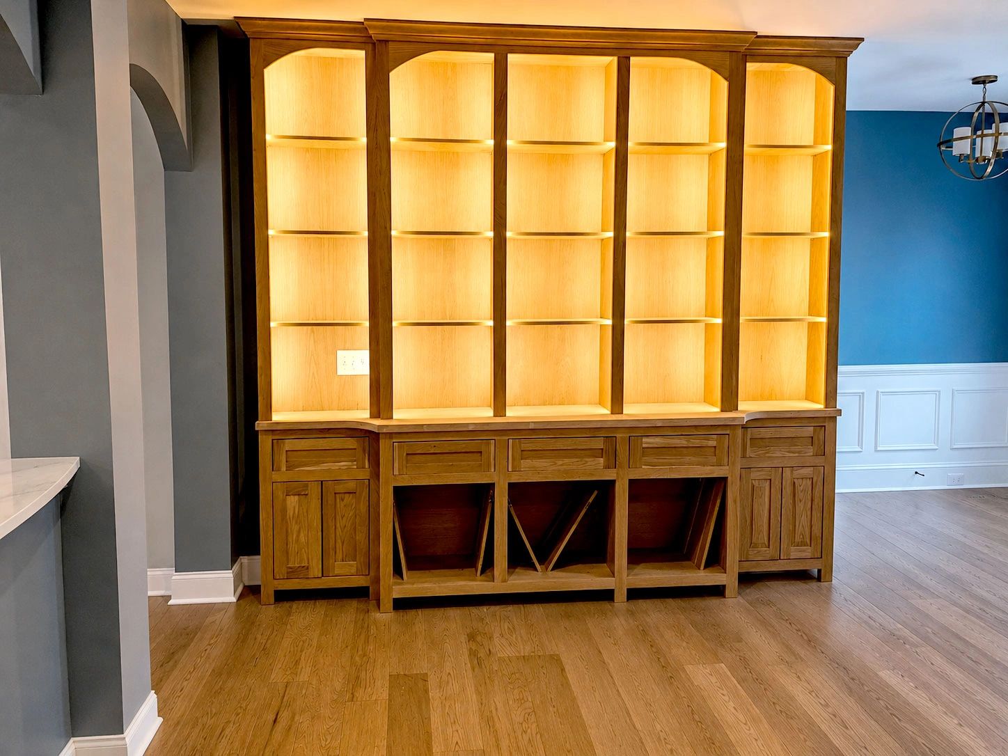 Illuminated wooden shelving unit in a modern room.