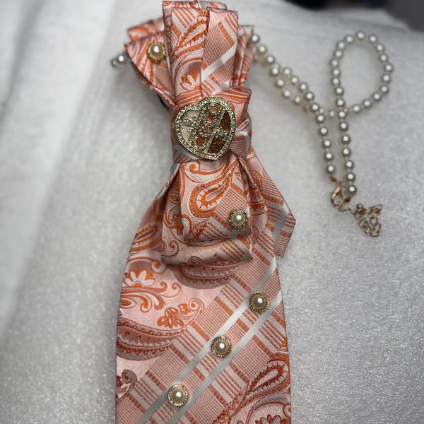 Elegant pink patterned tie with pearl and gold heart accents.