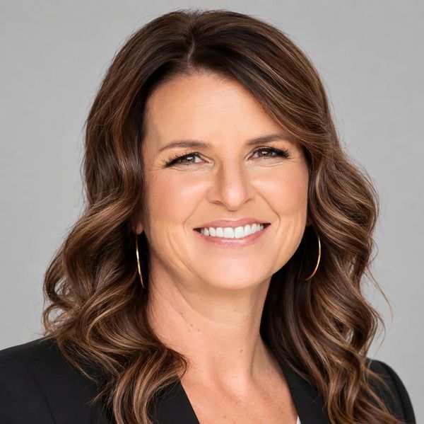Smiling woman with wavy brown hair and hoop earrings.