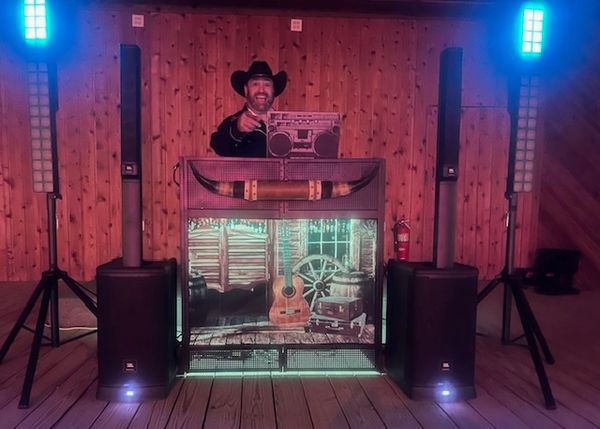 DJ in cowboy hat with vintage boombox and rustic music setup.