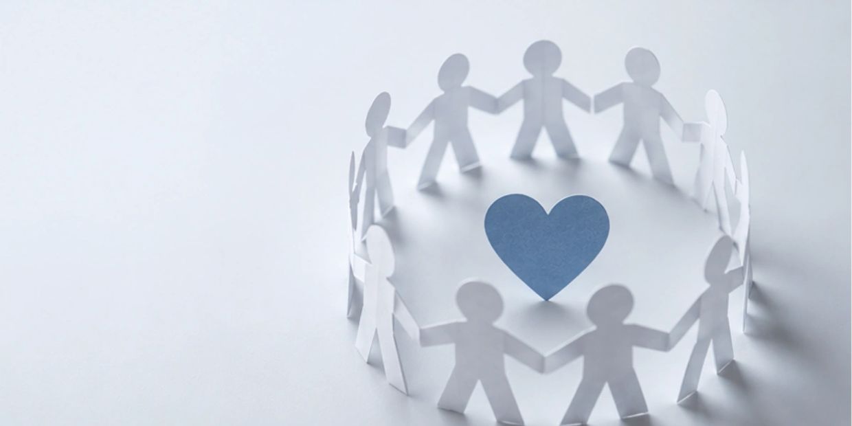 Paper cutout people in a circle with a blue heart in the center.