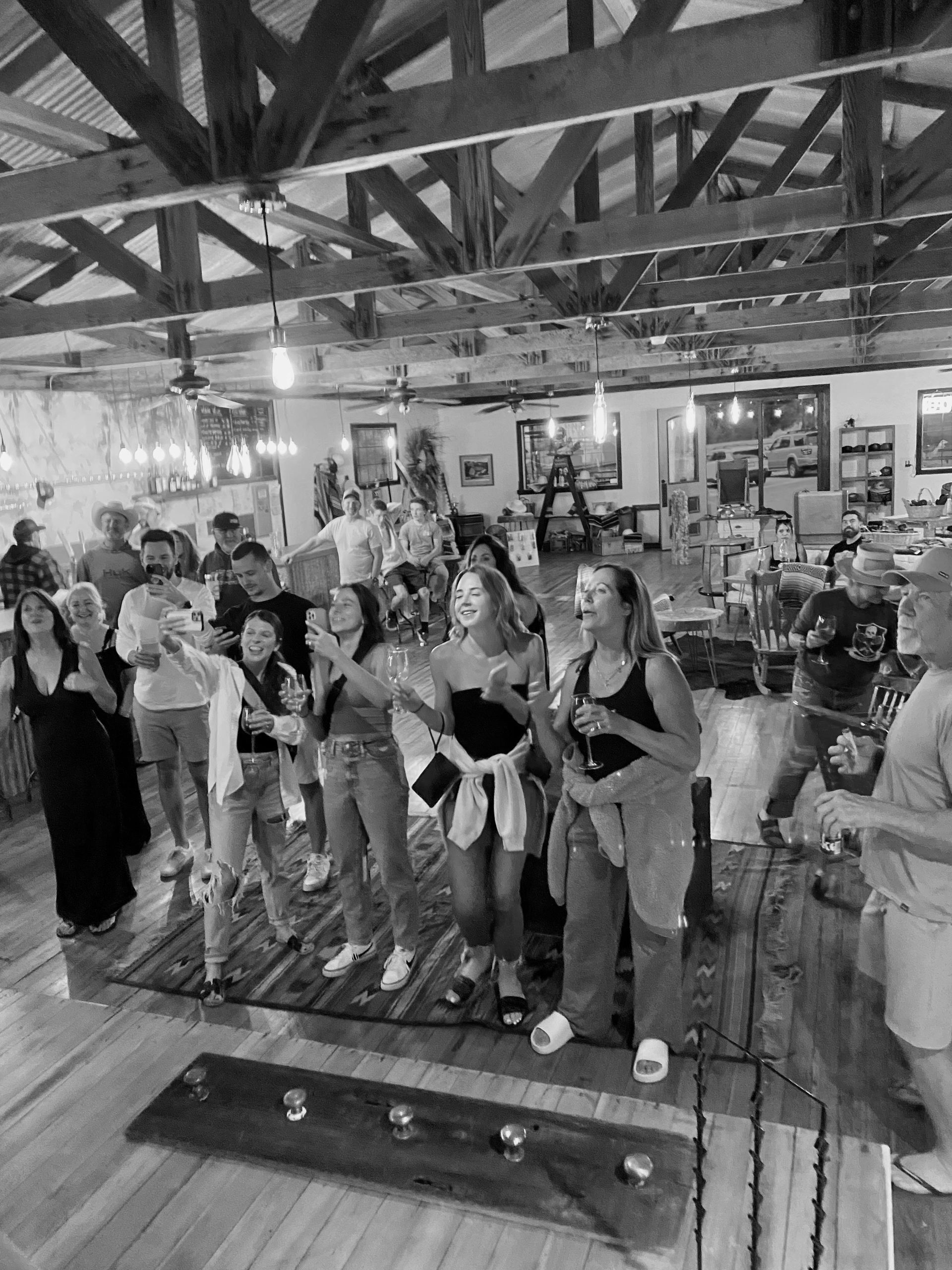Group of people enjoying a social gathering indoors, taking photos and drinking.